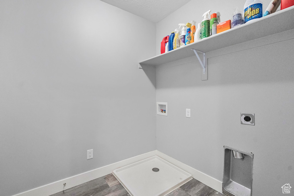 Washroom with dark wood-type flooring, washer hookup, hookup for an electric dryer, and a textured ceiling