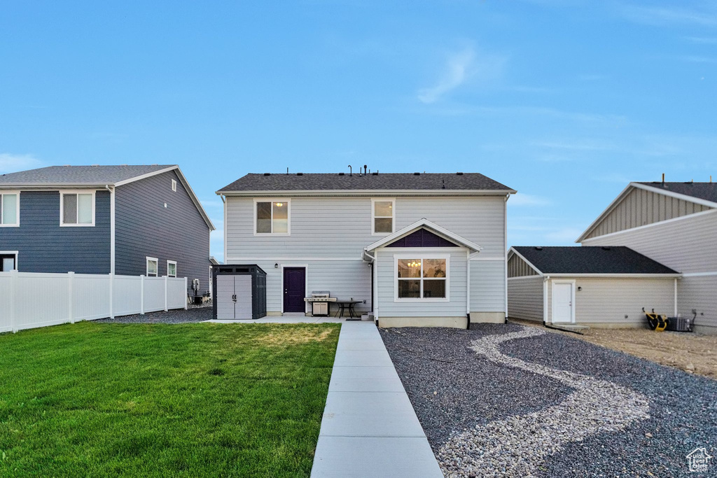 Rear view of property with a storage shed, a lawn, and a patio