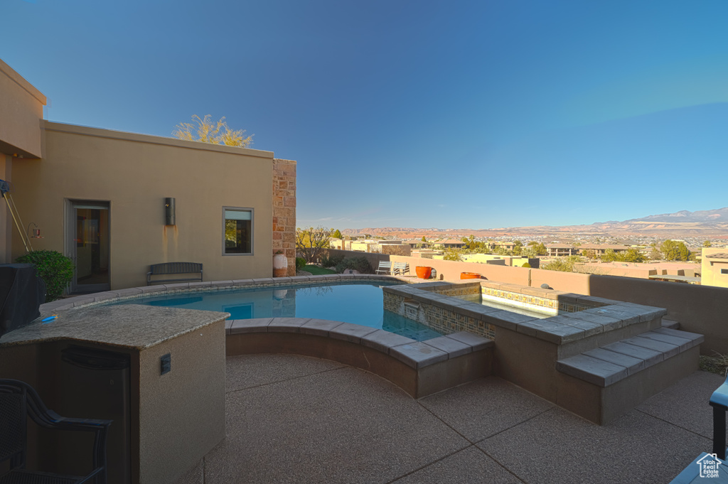 View of swimming pool featuring a mountain view, a patio area, and an in ground hot tub