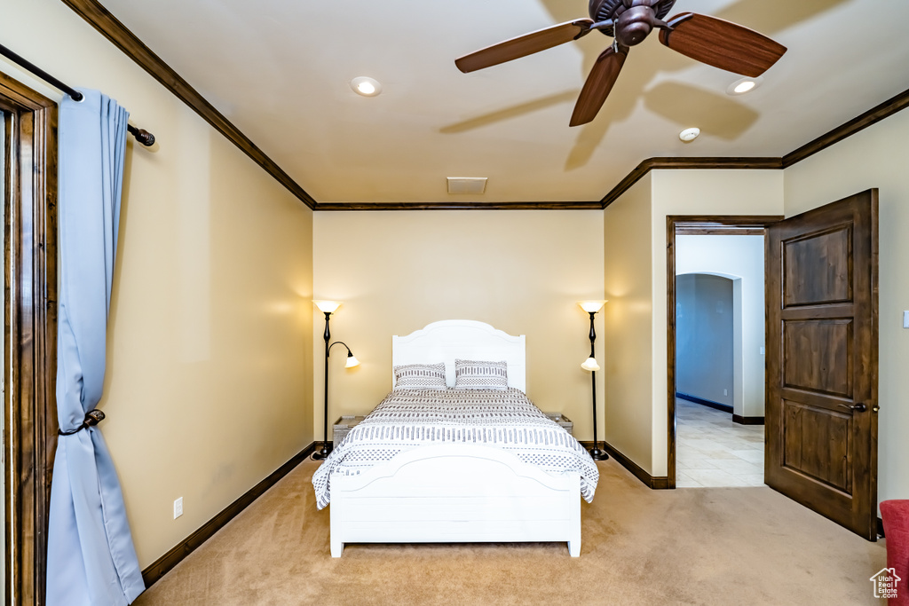 Bedroom with ceiling fan, light colored carpet, and ornamental molding