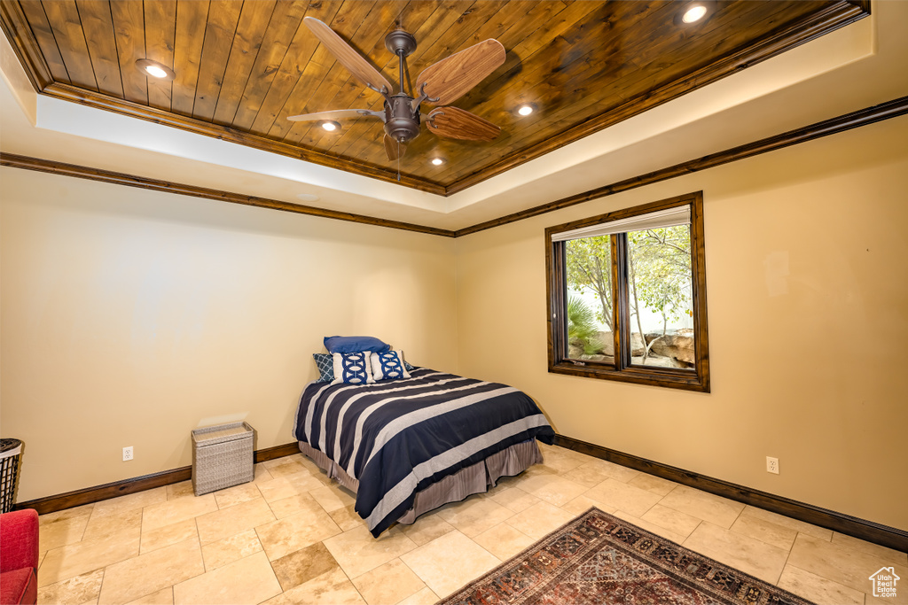 Bedroom featuring a raised ceiling, ceiling fan, wooden ceiling, and crown molding