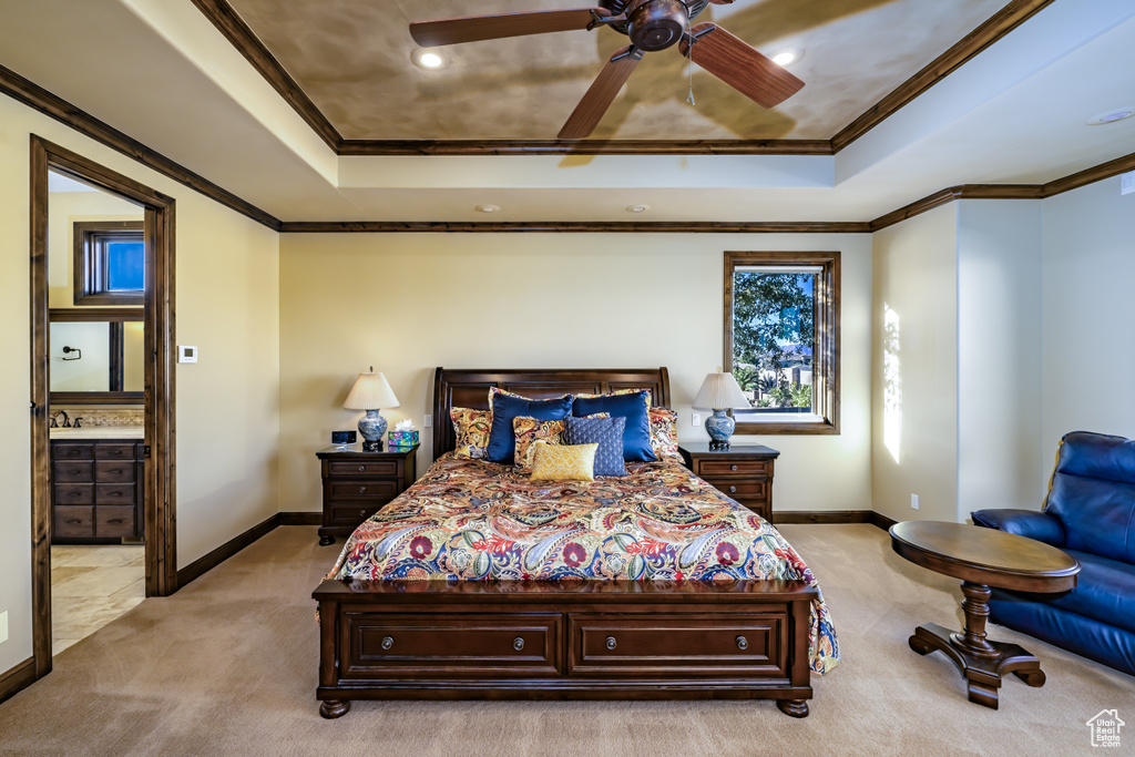 Carpeted bedroom with ornamental molding, a raised ceiling, ceiling fan, and connected bathroom