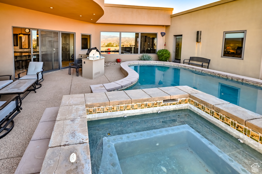 View of pool with a patio area and an in ground hot tub