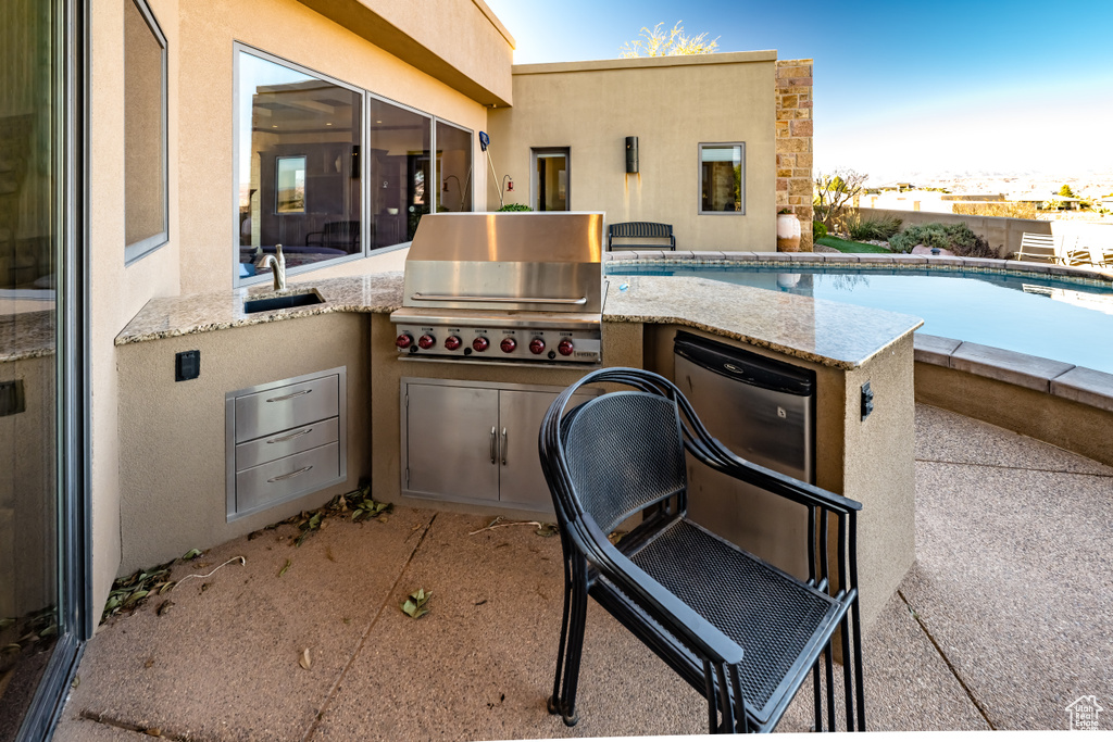 View of patio with sink, grilling area, a fenced in pool, and area for grilling
