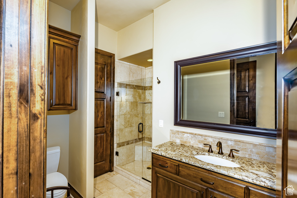 Bathroom featuring tile patterned flooring, an enclosed shower, backsplash, and vanity