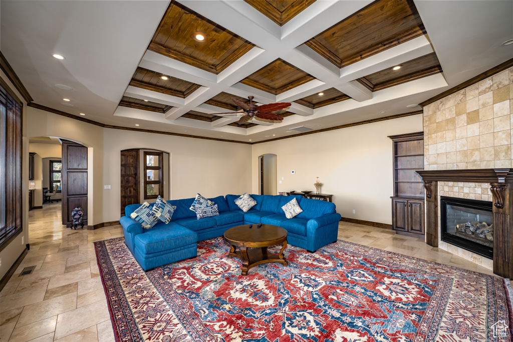 Living room featuring coffered ceiling, wooden ceiling, a tile fireplace, beamed ceiling, and ornamental molding