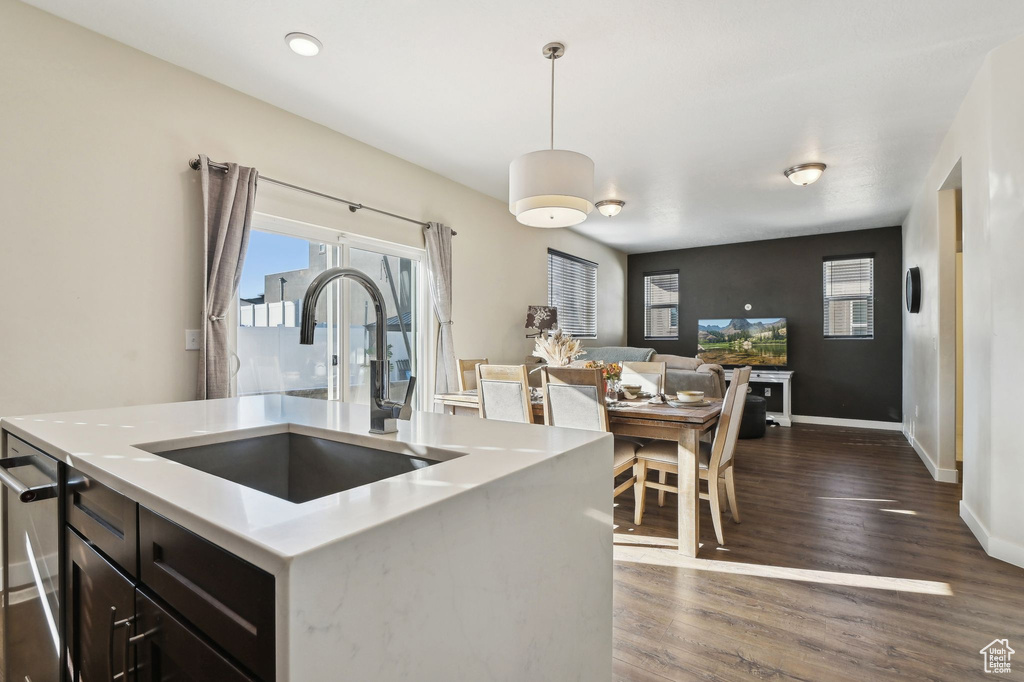 Kitchen featuring dark hardwood / wood-style floors, a kitchen island with sink, hanging light fixtures, stainless steel dishwasher, and sink