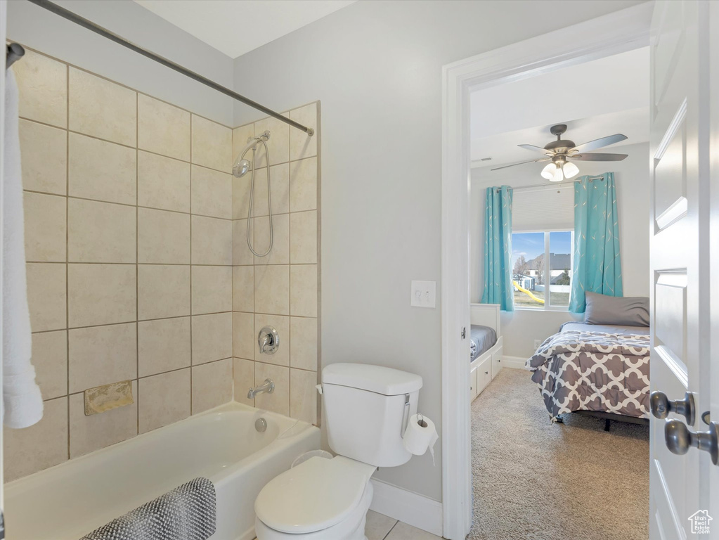 Bathroom featuring toilet, tiled shower / bath combo, and ceiling fan