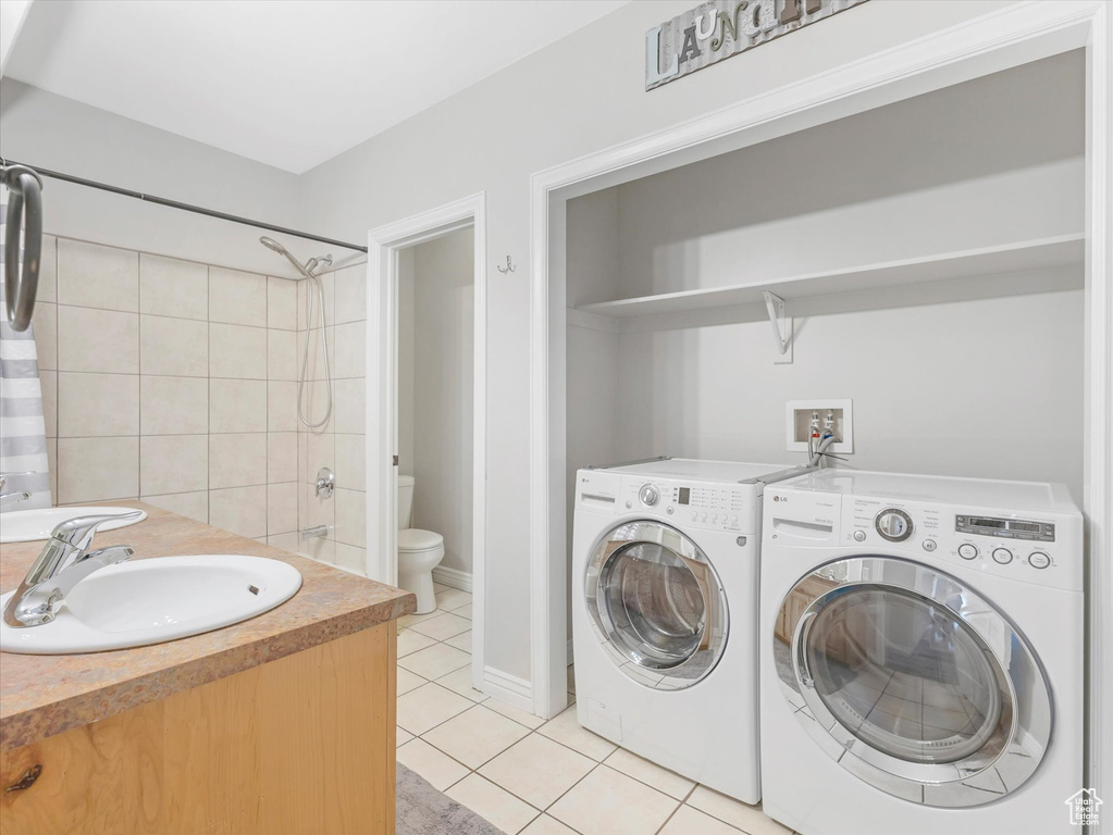 Laundry area with sink, washing machine and dryer, and light tile patterned floors