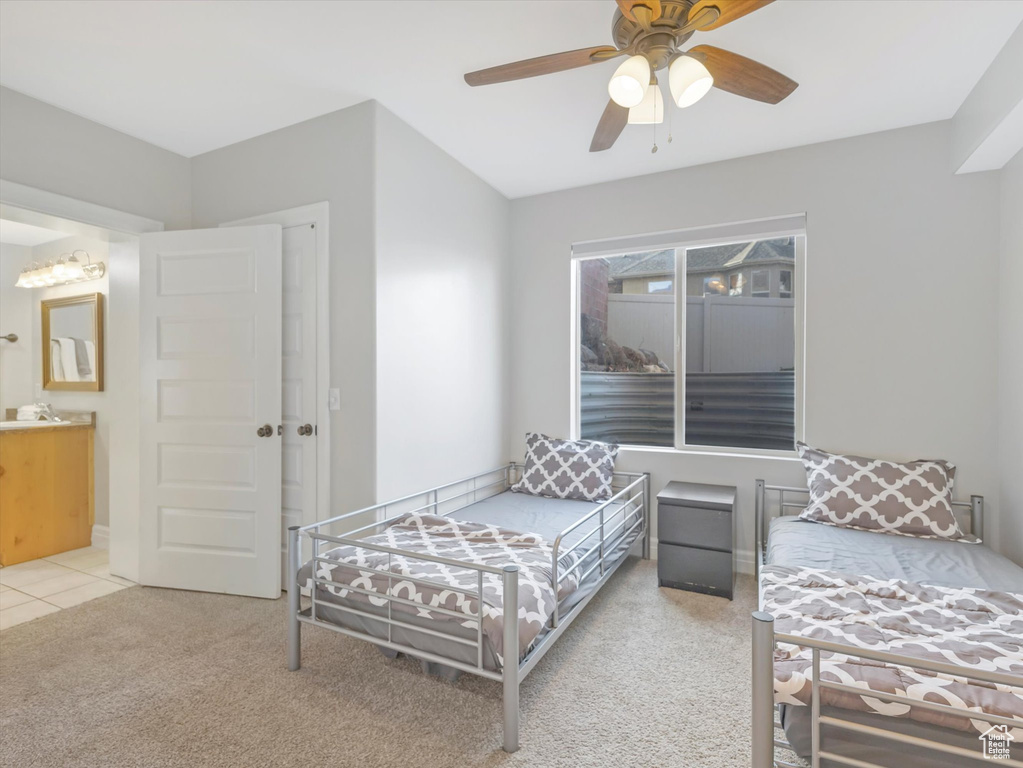 Bedroom with ensuite bathroom, ceiling fan, light carpet, and sink