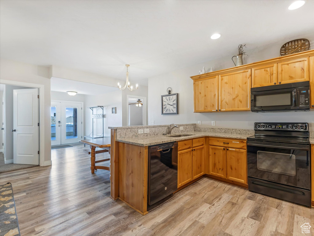 Kitchen featuring black appliances, light hardwood / wood-style flooring, kitchen peninsula, and sink