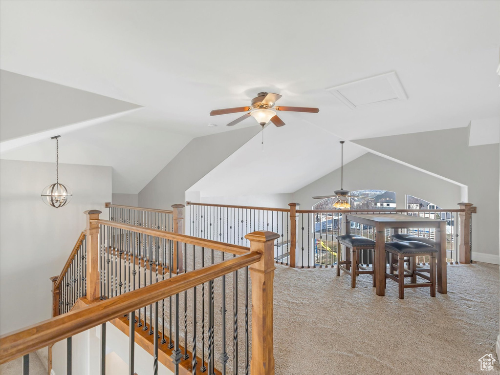 Hall with light colored carpet, vaulted ceiling, and a chandelier