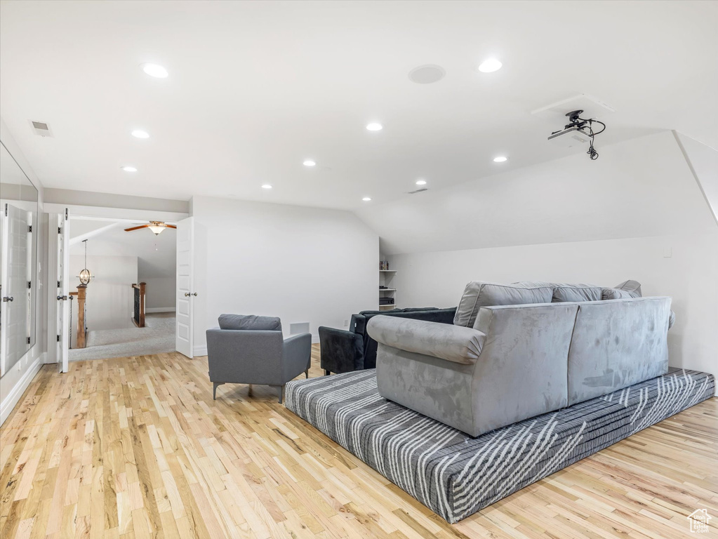 Home theater room featuring lofted ceiling, light wood-type flooring, and ceiling fan