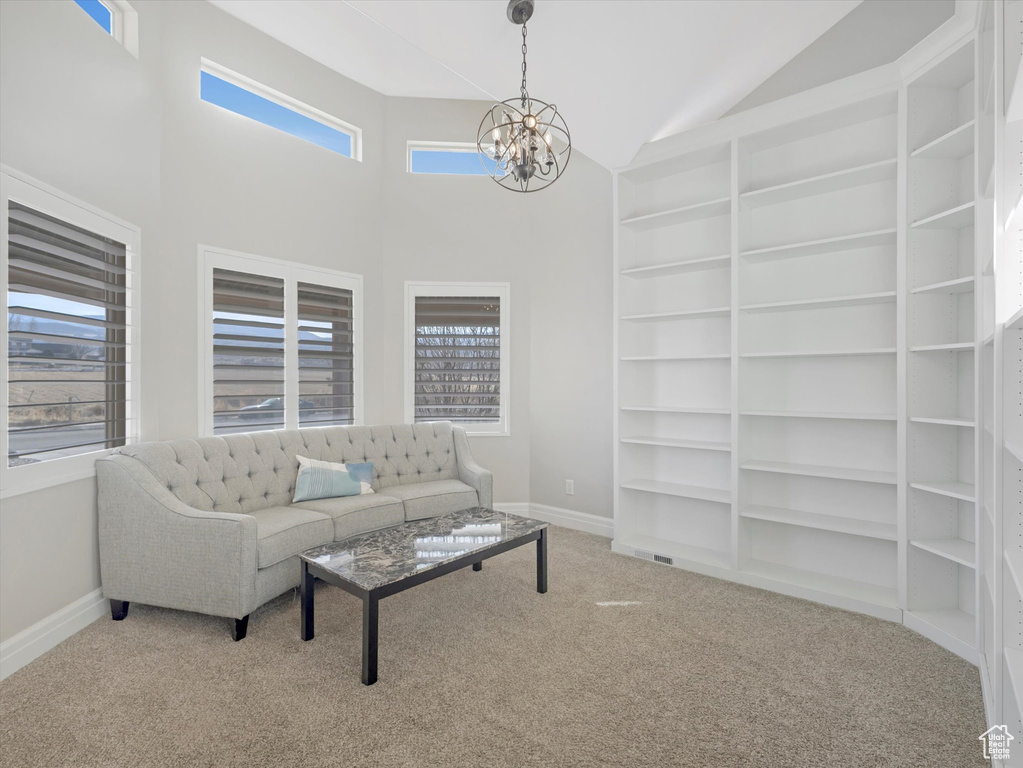 Living room featuring lofted ceiling, built in shelves, a chandelier, and carpet