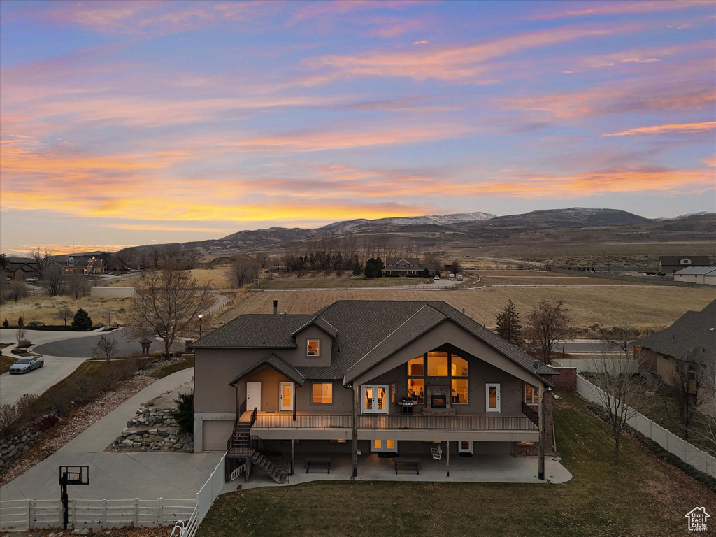 Back house at dusk featuring a patio and a mountain view