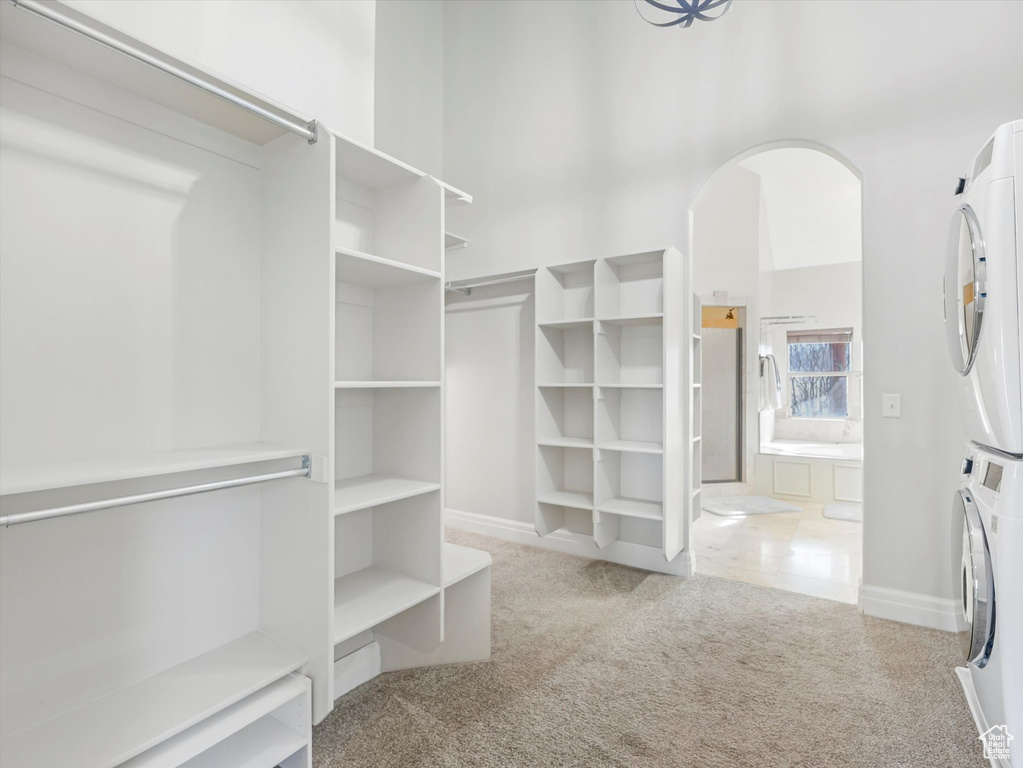Spacious closet featuring stacked washing maching and dryer and carpet