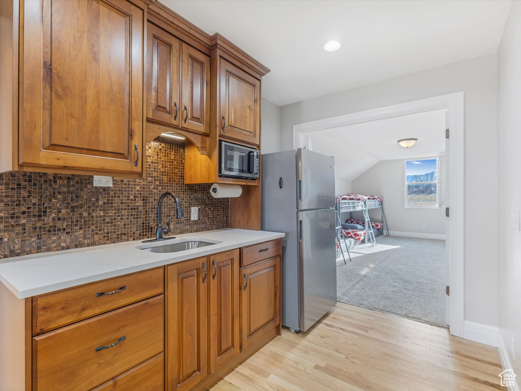Kitchen featuring sink, appliances with stainless steel finishes, lofted ceiling, decorative backsplash, and light colored carpet