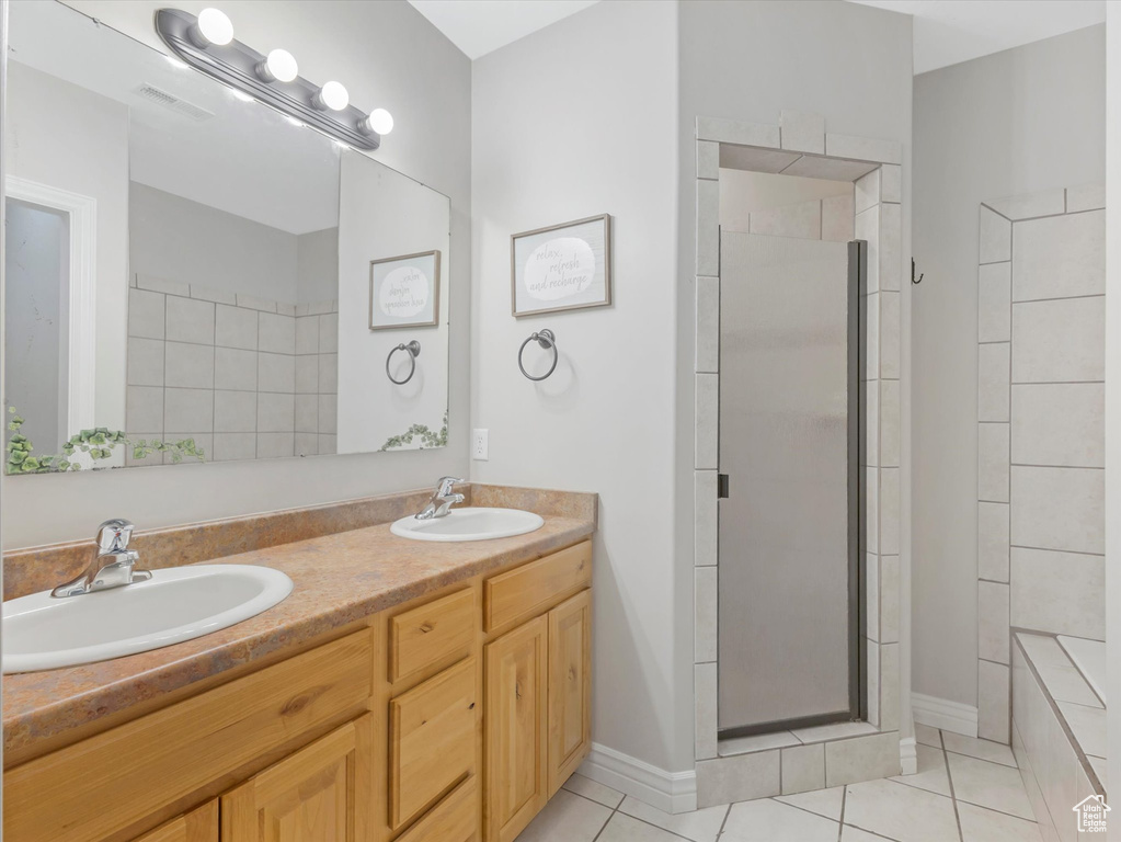 Bathroom featuring tile patterned flooring, tiled shower, and vanity