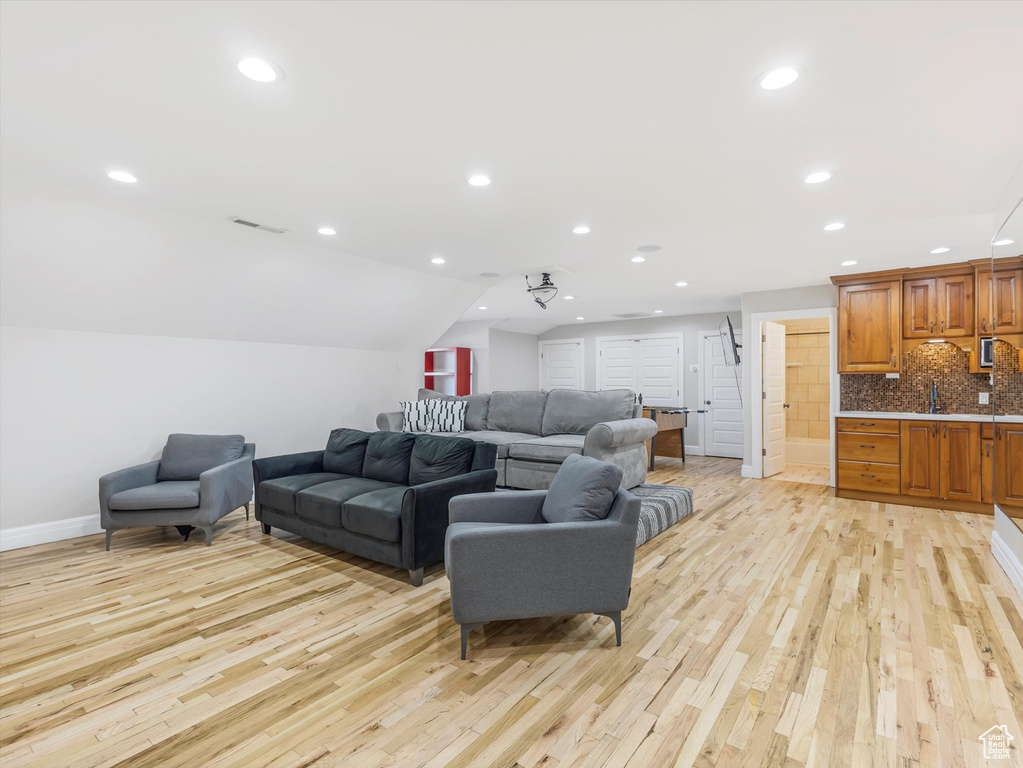 Living room featuring sink, light hardwood / wood-style floors, ceiling fan, and vaulted ceiling
