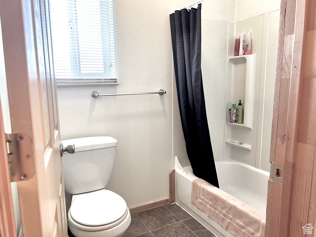 Bathroom with toilet, tile patterned flooring, and shower / bath combo with shower curtain