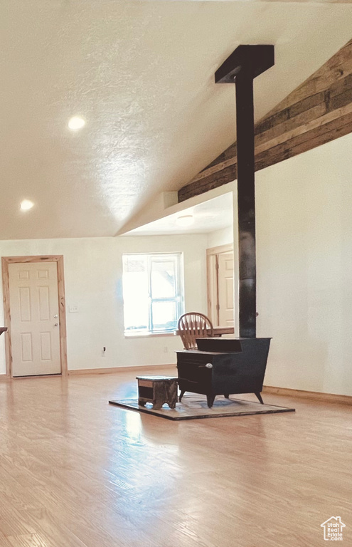 Dining area featuring a wood stove, a textured ceiling, light hardwood / wood-style flooring, and vaulted ceiling