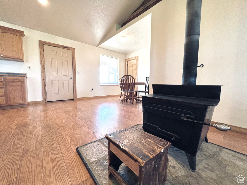 Misc room with a textured ceiling, lofted ceiling, and light wood-type flooring