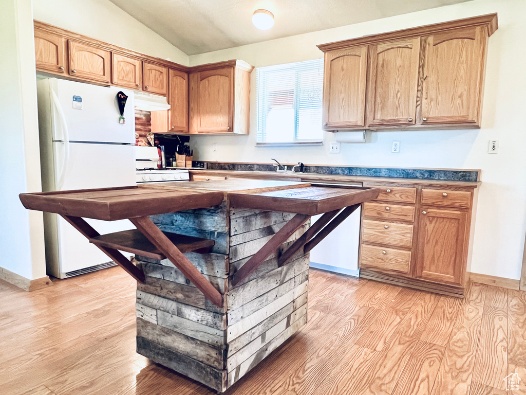 Kitchen with light wood-type flooring, lofted ceiling, and white appliances