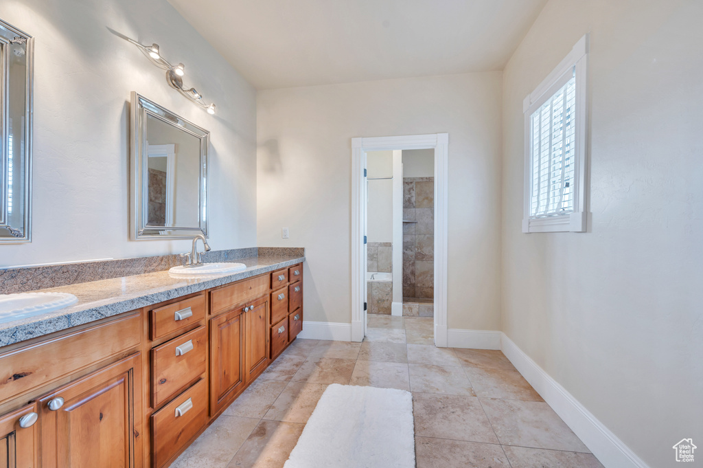 Bathroom with tile patterned flooring, vanity, and a tile shower