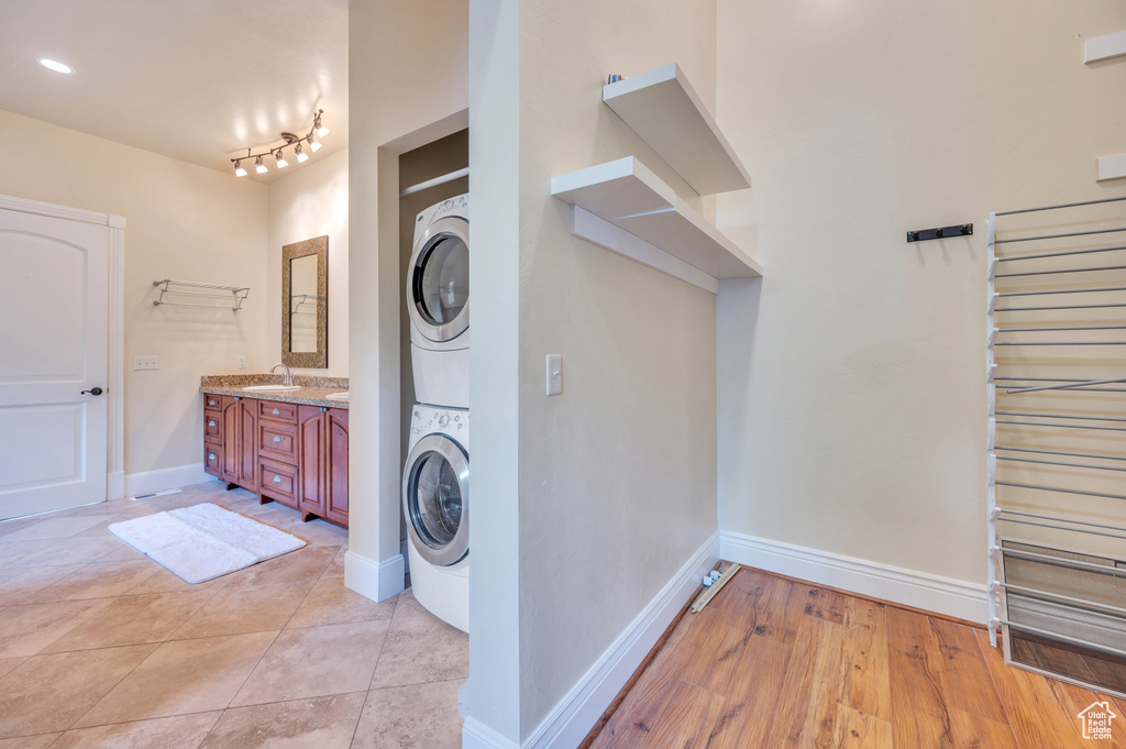 Laundry room featuring stacked washer / drying machine, light tile patterned floors, and sink