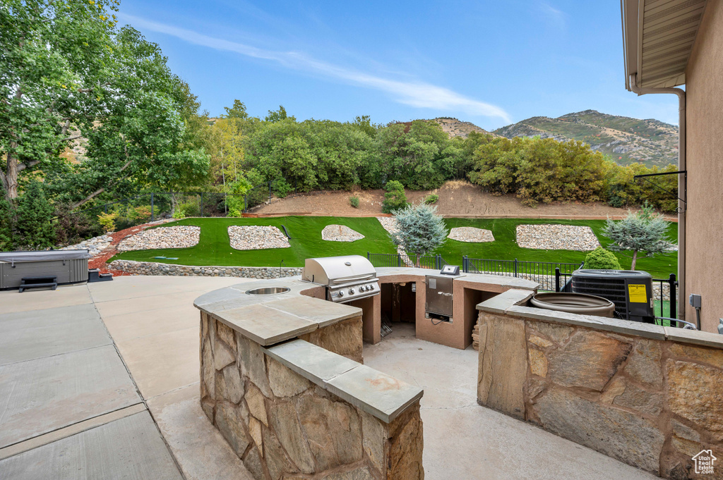 View of patio / terrace with area for grilling, central air condition unit, grilling area, a mountain view, and a hot tub