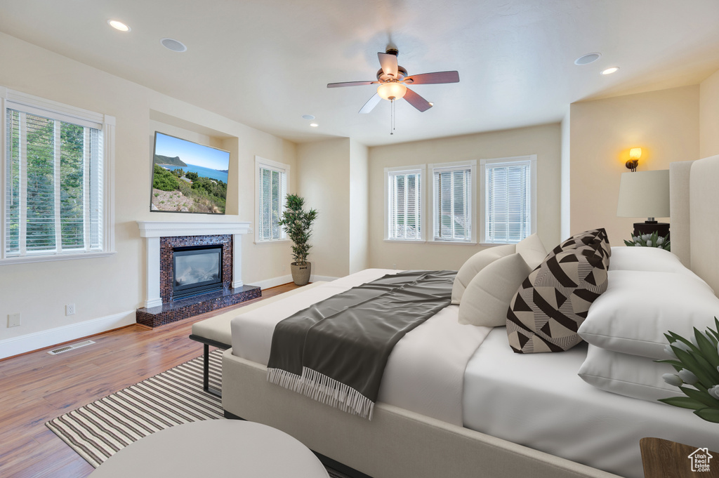 Bedroom featuring a tiled fireplace, ceiling fan, and hardwood / wood-style floors