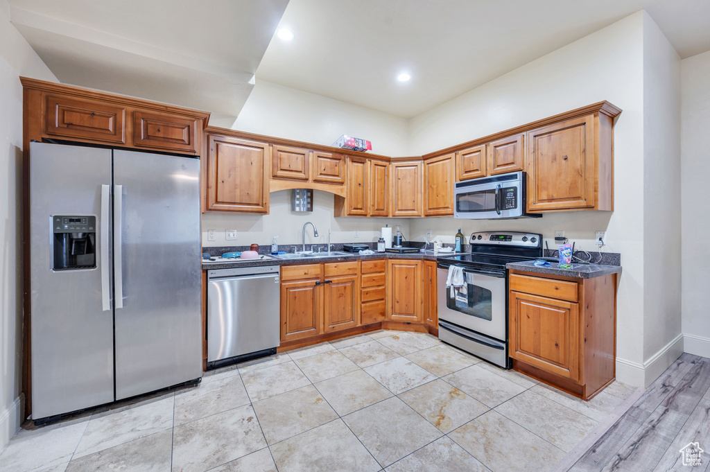 Kitchen featuring dark stone countertops, sink, and stainless steel appliances