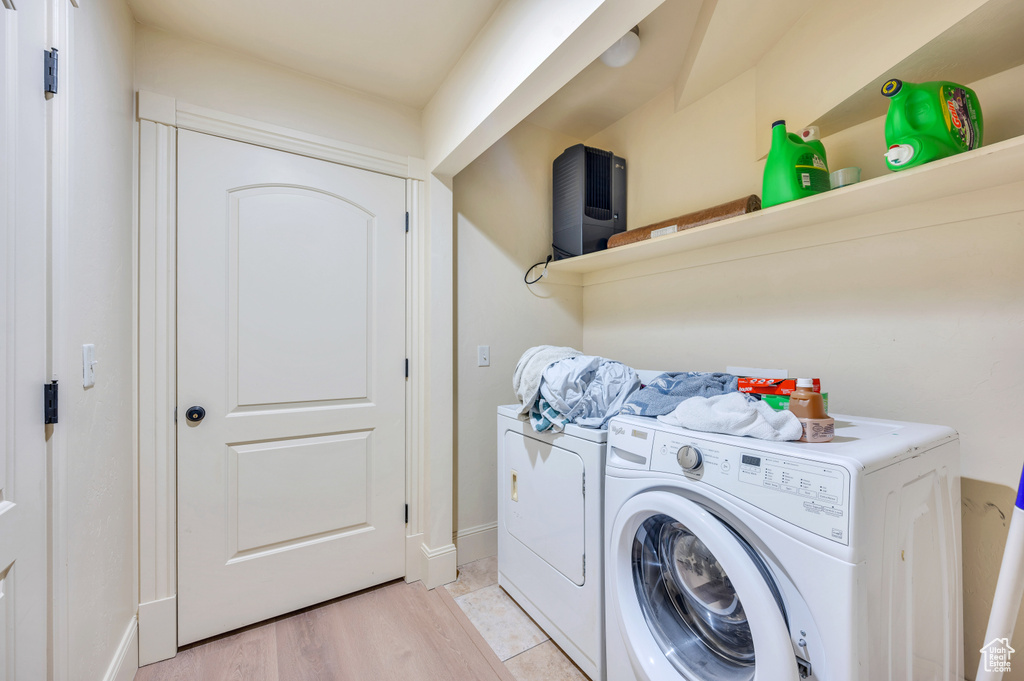 Laundry area featuring washer and clothes dryer and light hardwood / wood-style flooring