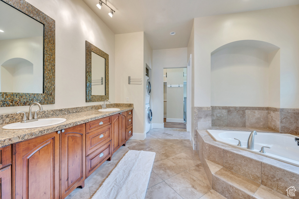 Bathroom with stacked washer and dryer, vanity, and a relaxing tiled tub