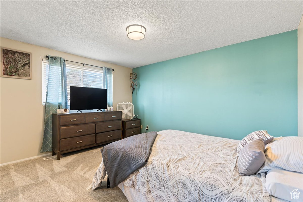 Bedroom with light carpet and a textured ceiling