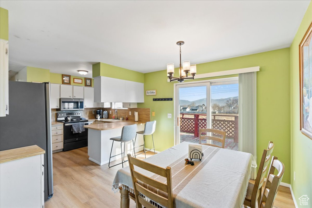 Dining space featuring an inviting chandelier, light hardwood / wood-style flooring, and sink