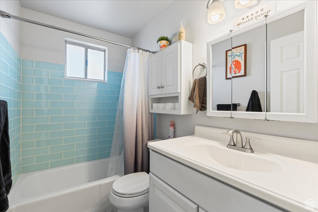 Full bathroom featuring toilet, shower / bathtub combination with curtain, and vanity