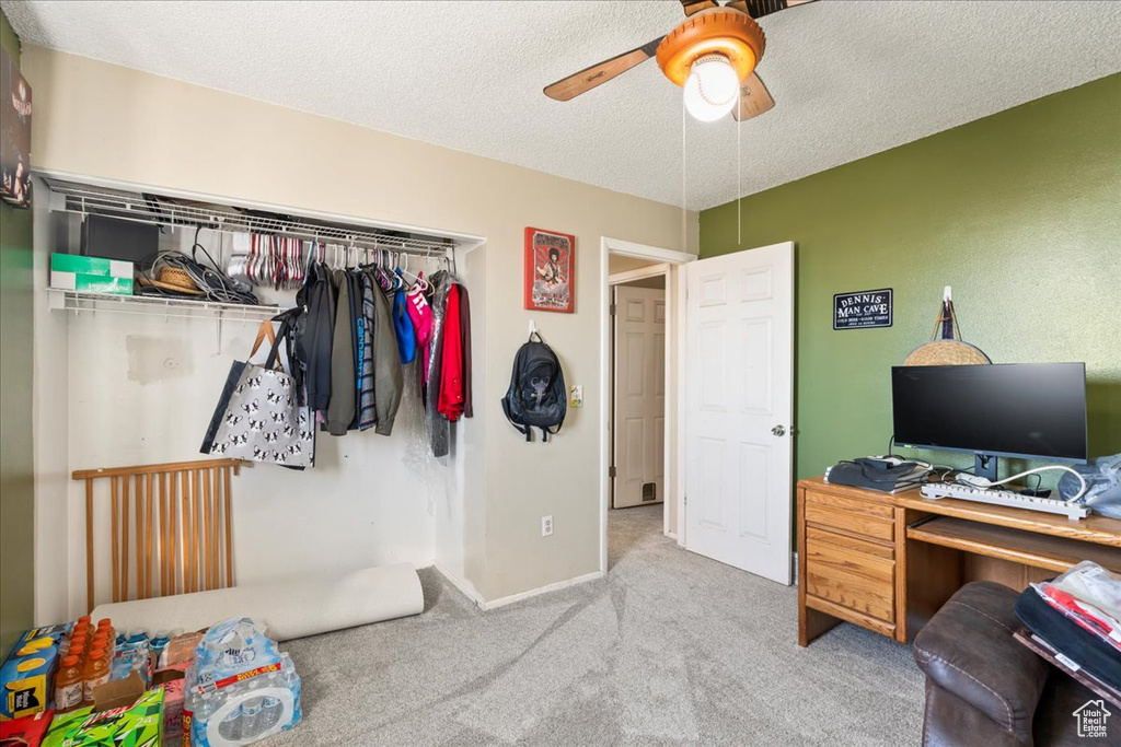 Carpeted bedroom featuring ceiling fan and a textured ceiling