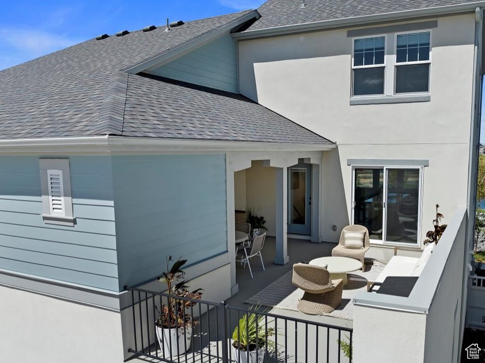 Back of property featuring a water view, a balcony, and outdoor lounge area