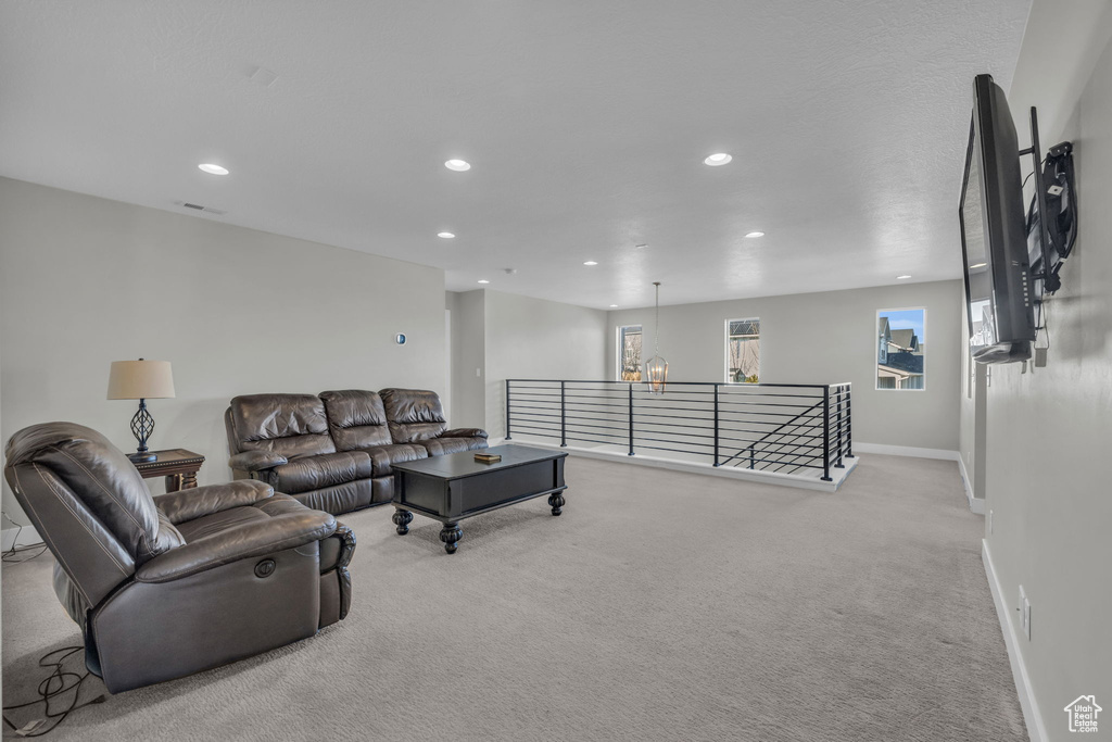 Carpeted living room with an inviting chandelier