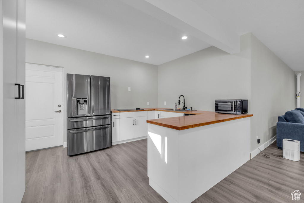 Kitchen featuring kitchen peninsula, sink, white cabinetry, light hardwood / wood-style flooring, and stainless steel fridge with ice dispenser