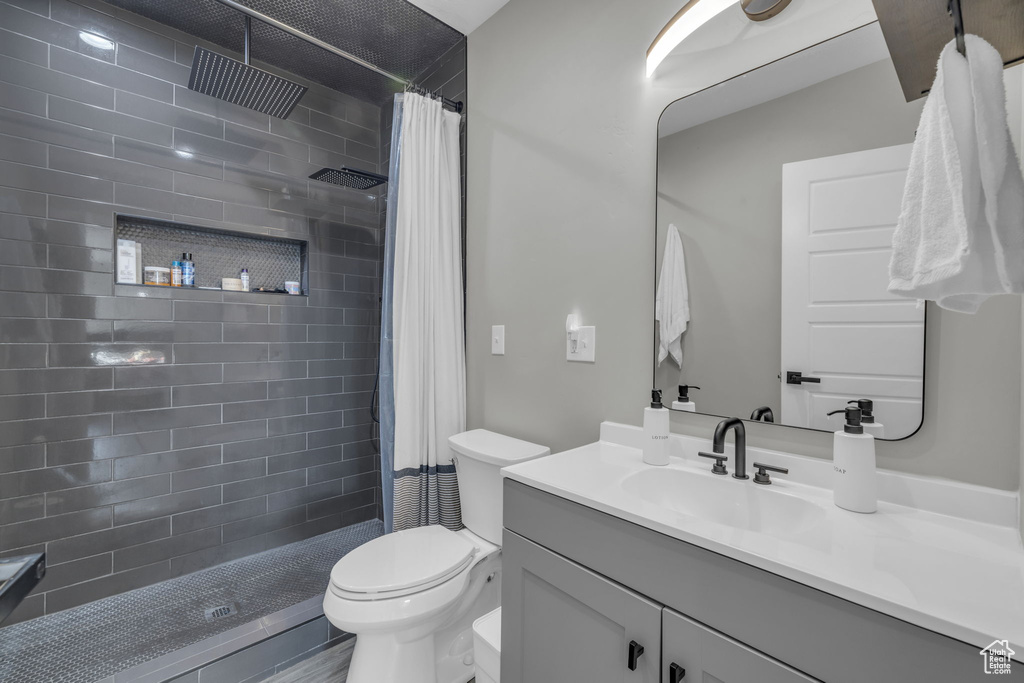 Bathroom with toilet, vanity, and a shower with shower curtain