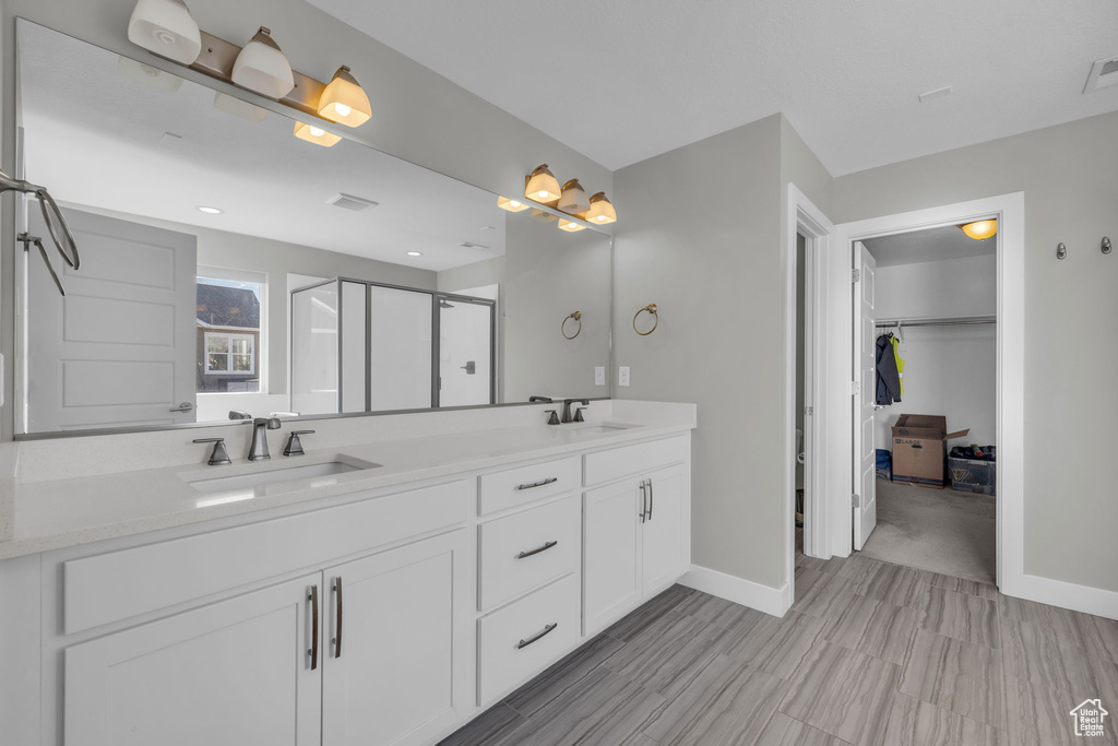 Bathroom featuring a shower with shower door and vanity