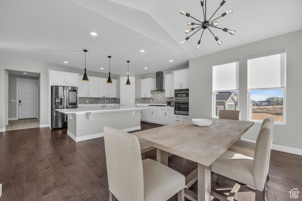 Dining room featuring vaulted ceiling, dark hardwood / wood-style flooring, sink, and a chandelier