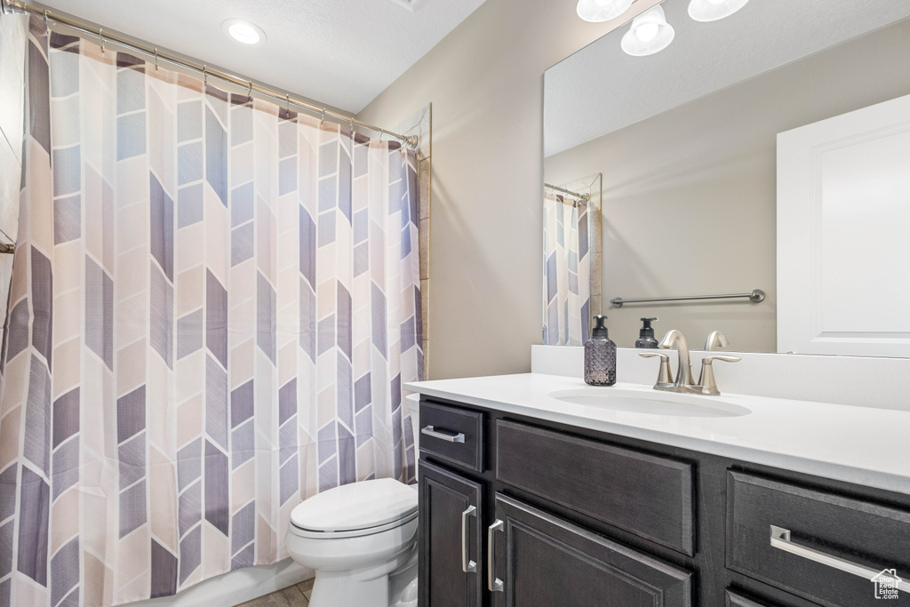 Bathroom with toilet, vanity, and curtained shower