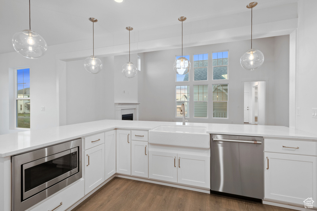 Kitchen with stainless steel appliances, wood finished floors, a fireplace, and light countertops