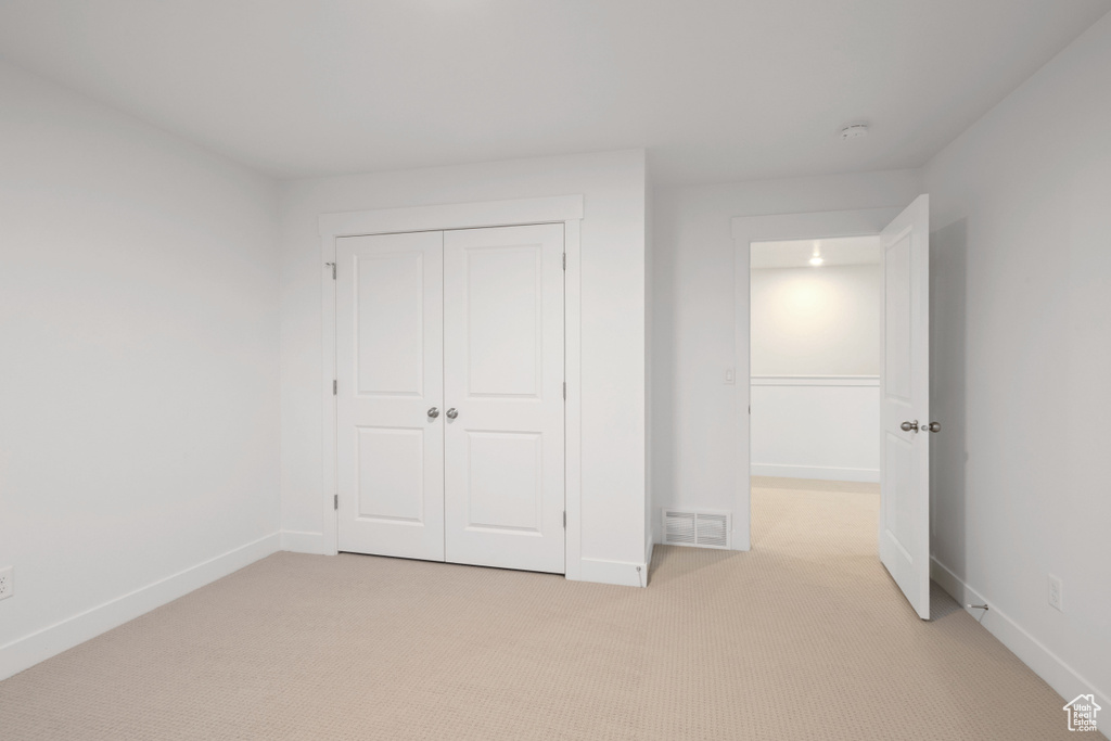 Unfurnished bedroom with light carpet and a closet