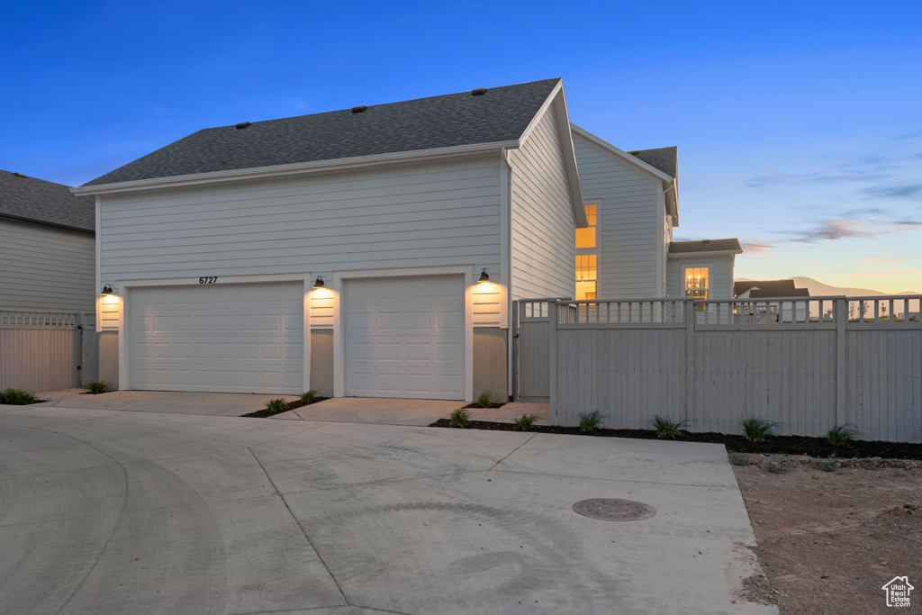 Property exterior at dusk with a garage and concrete driveway