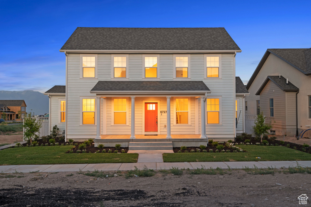 View of front facade featuring covered porch, a front lawn, and a shingled roof