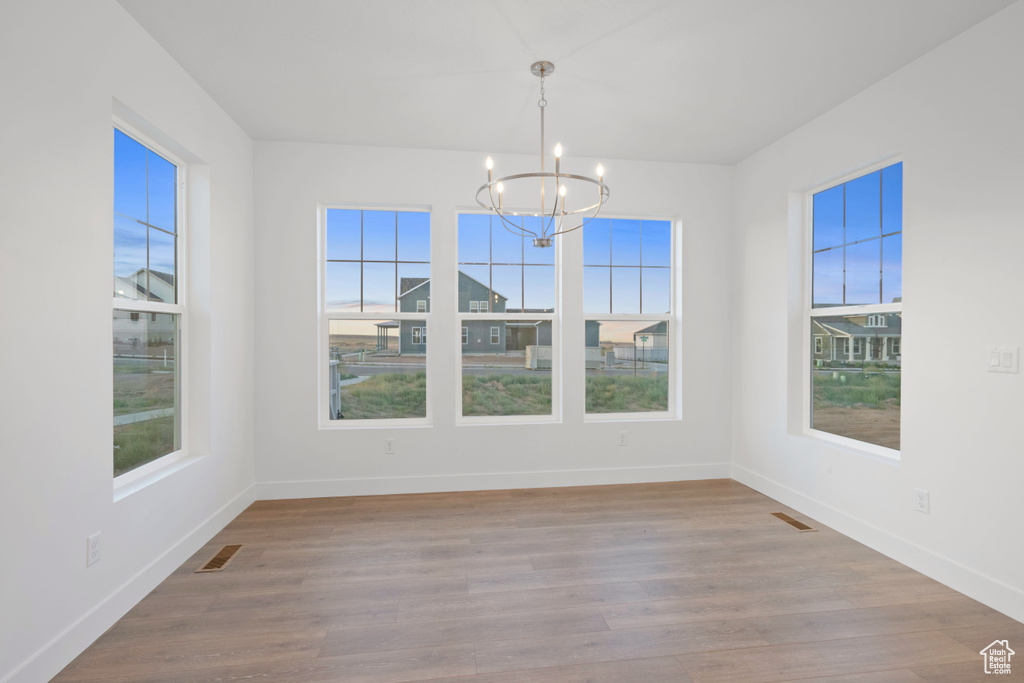 Unfurnished dining area with a chandelier and wood finished floors